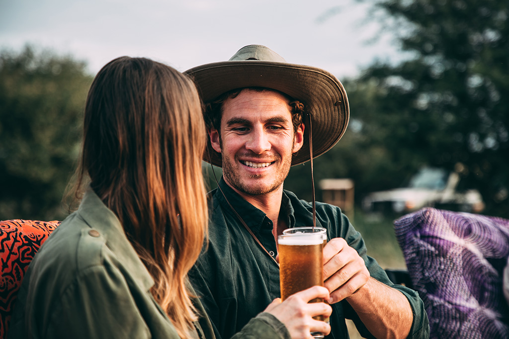 タンザニアで、見つめ合いながらビールグラスで乾杯するカップルのクローズアップ