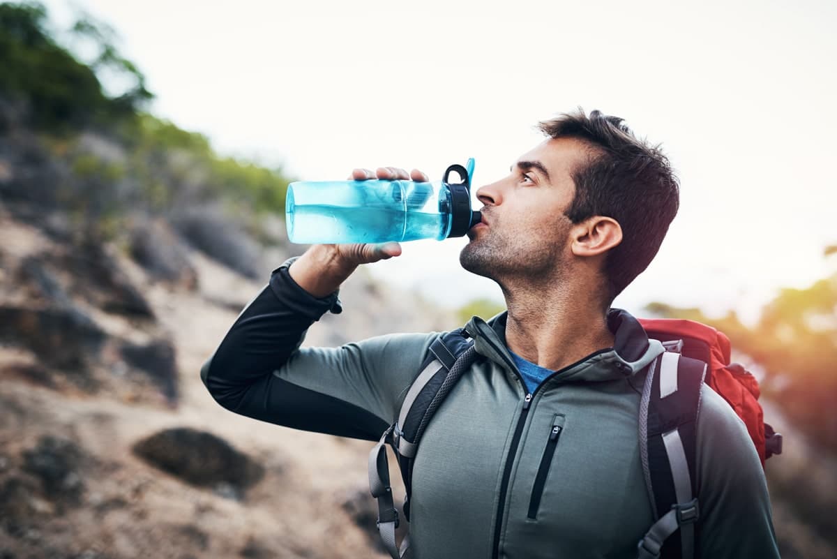Männlicher Bergsteiger trinkt Wasser auf dem Kilimandscharo