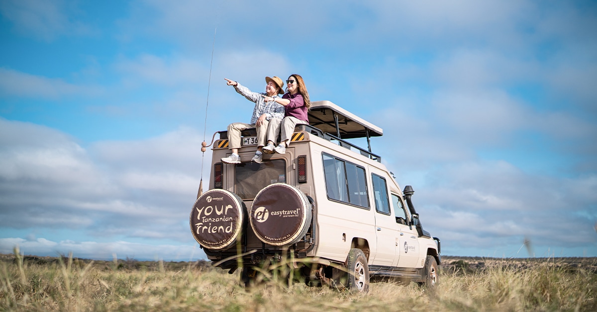 Couple sitting on top of the Easy Travel safari vehicle at Tarangire National Park, Tanzania