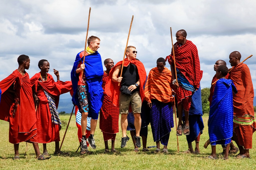 坦桑尼亚米库米国家公园的游客与马赛战士一起跳跃