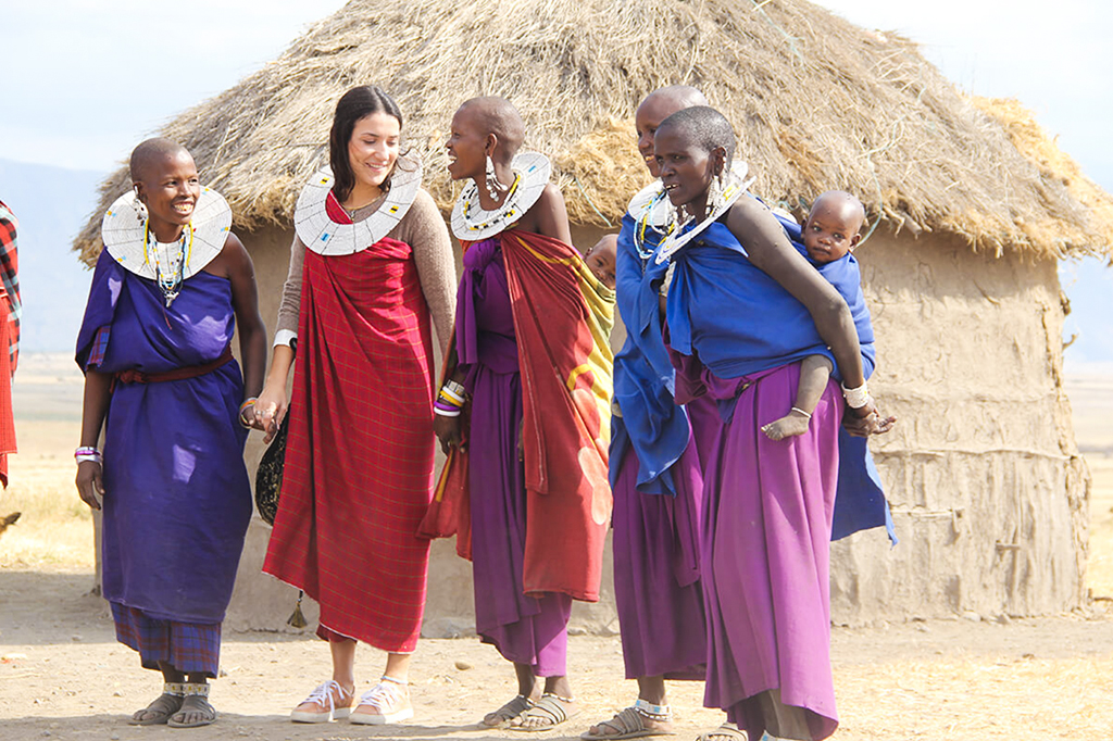 Een jonge vrouwelijke toerist doet mee aan een traditionele dans met de Maasai in Mto wa Mbu, Tanzania.