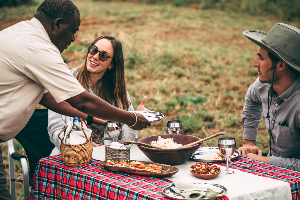 Tourist couple having a picnic in arusha national park, tanzania