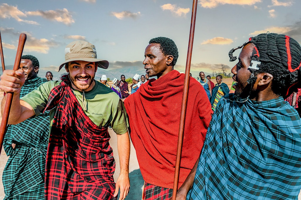 Touristen in Massai-Kostümen mit Massai-Kriegern am West-Kilimanjaro in Tansania