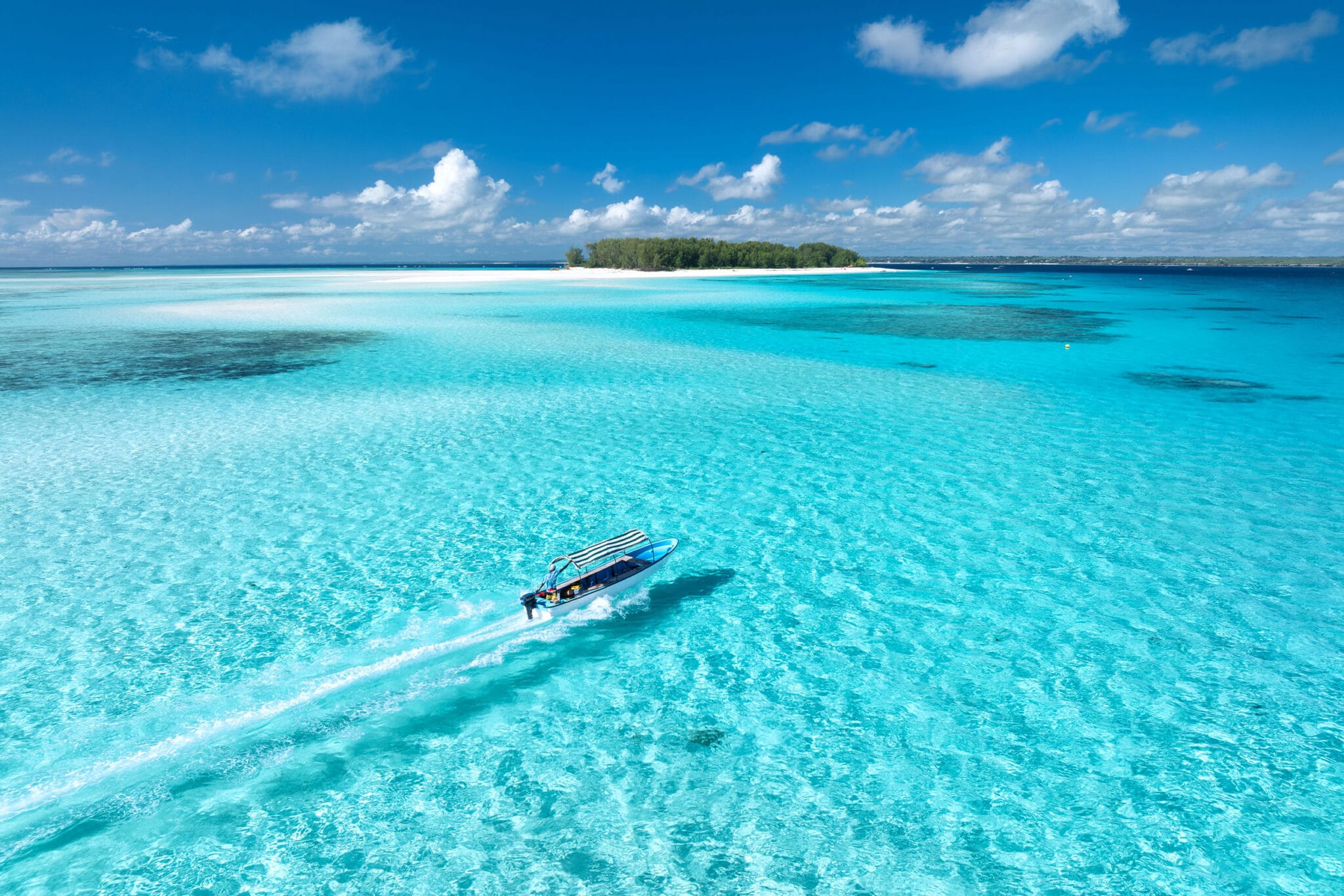 Aerial view of a boat floating in crystal-clear waters near Mnemba Island