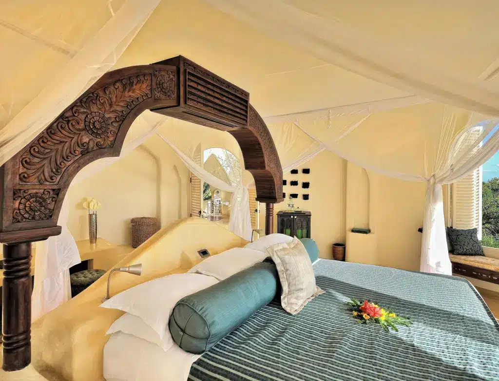 Lussuosa camera da letto a Elewana Kilindi Zanzibar con letto a baldacchino, arredi eleganti e vista panoramica. Perfetta per un rifugio tropicale.