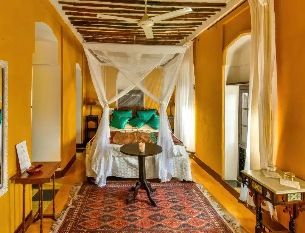 Chambre élégante à Kholle House, en Tanzanie, avec un lit à baldaquin, une décoration colorée et un mobilier traditionnel.