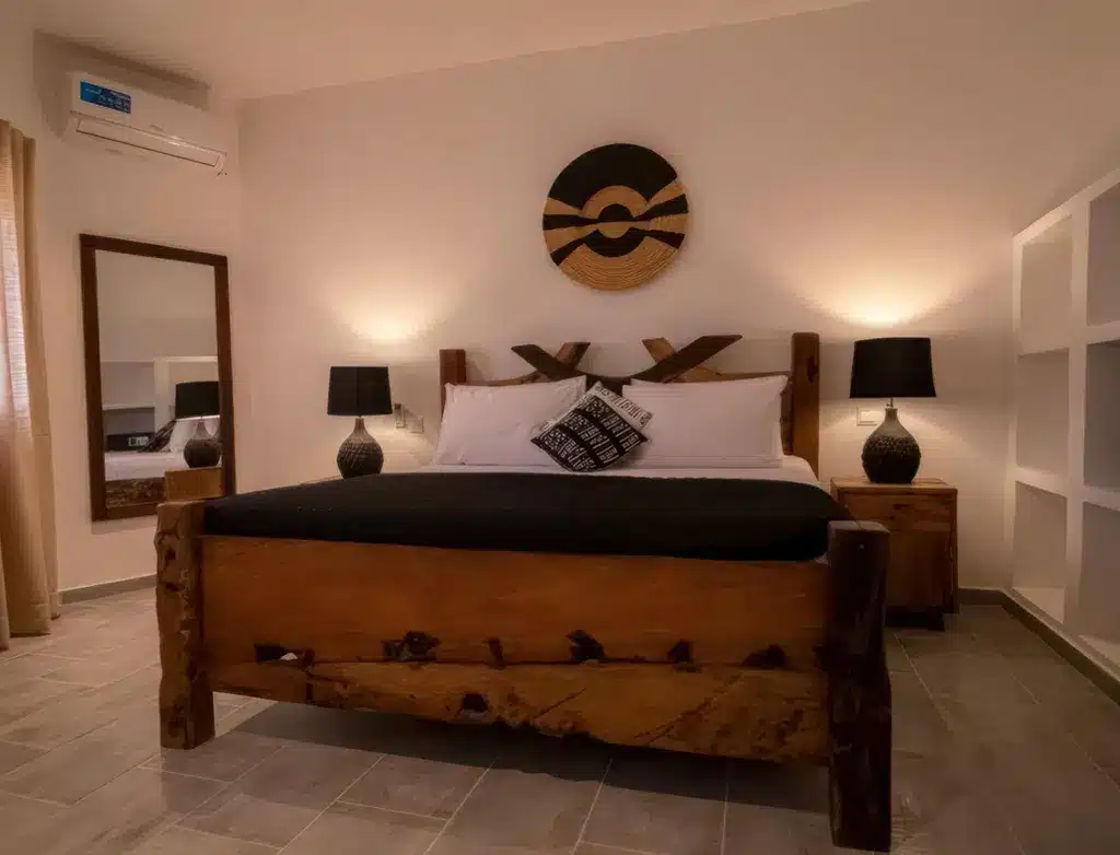 Уютный номер в отеле Tamu Tamu Boutique Hotel с кроватью из натурального дерева, стильным декором, теплым освещением и современными удобствами...