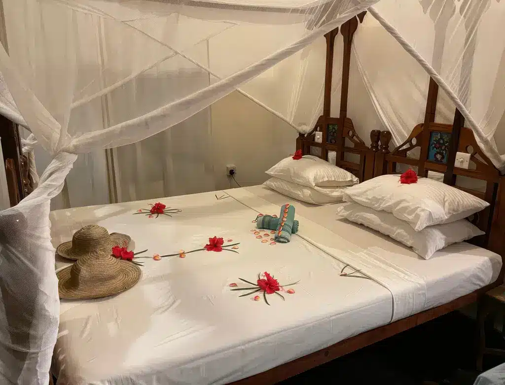Gezellige hotelkamer op Zanzibar met een hemelbed, bloemversiering en strohoeden, die een serene, ontspannen sfeer uitstraalt.