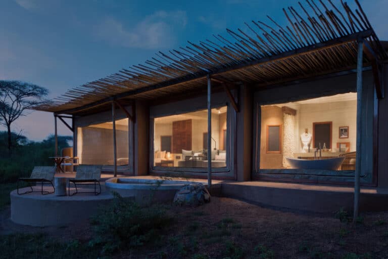 Luxuriöse Safari-Lodge in der Abenddämmerung mit großen Fenstern, Sitzgelegenheiten im Freien und einer ruhigen, natürlichen Umgebung.