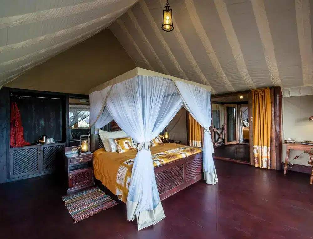 Luxuriöses Zelt-Lodge-Zimmer mit Himmelbett, Holzböden und elegantem Dekor am Ndutu-See. Gemütliches und einladendes Ambiente.