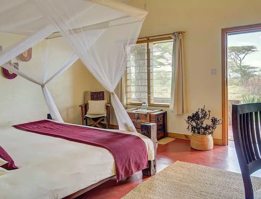 Safari lodge kamer met hemelbed, houten meubels en een openslaande deur die uitzicht biedt op de Afrikaanse savanne. Gezellig en uitnodigend...