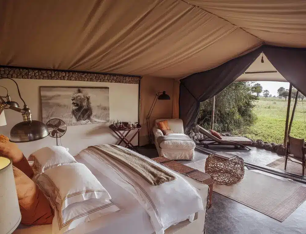 Luxuriöses Safari-Lodge-Zimmer mit gemütlichem Bett, elegantem Dekor und freiem Blick auf die afrikanische Savannenlandschaft.