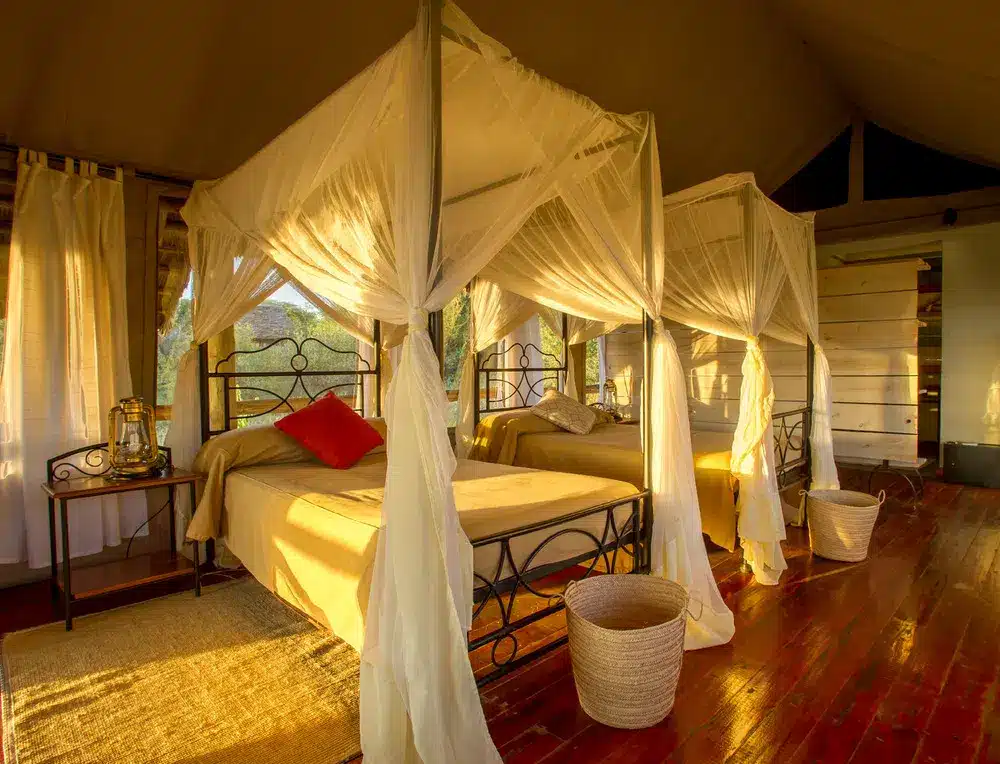Lujosa habitación en tienda de campaña con camas con dosel, pisos de madera y luz natural en el lago Burunge.