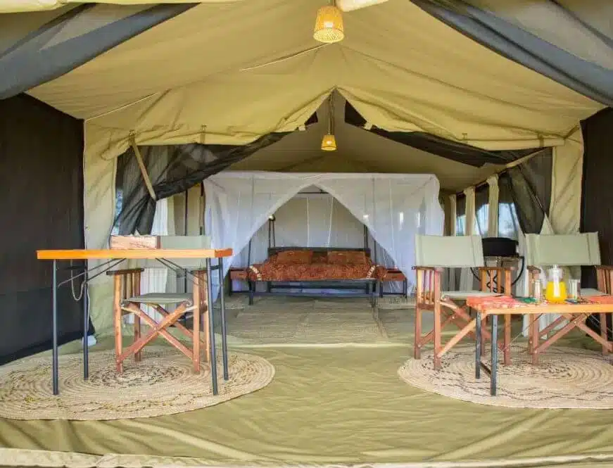 Das Interieur eines Safari-Zeltes mit Stühlen, Tischen und einem Bett besticht durch natürliche Dekoration und stimmungsvolle Beleuchtung und schafft so eine gemütliche Camp-Atmosphäre...