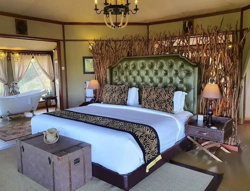 Chambre luxueuse dans un lodge de safari à Tarangire, en Tanzanie, avec un lit moelleux, un décor rustique, un lustre et une baignoire îlot.