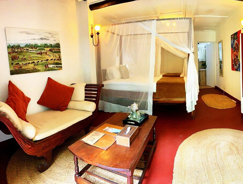 Elegantes Lodge-Zimmer mit Himmelbett, gemütlichen Sitzgelegenheiten und rustikaler Einrichtung in der Mount Meru Game Lodge.