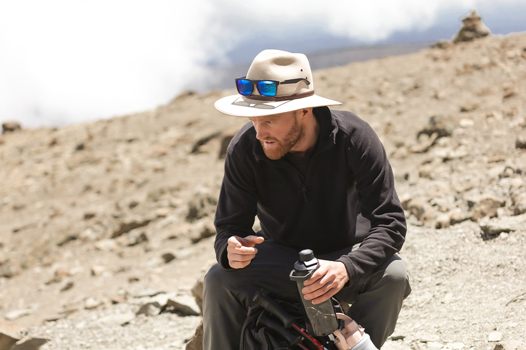 A Kilimanjaro hiker wearing a brimmed hat while trekking A Kilimanjaro hiker wearing a brimmed hat while trekking