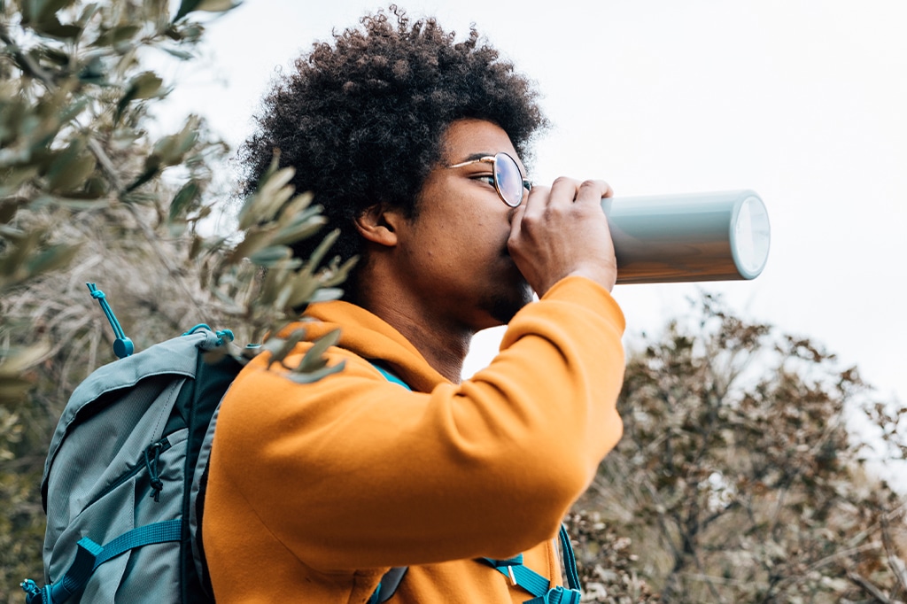 一位年轻的徒步旅行者从他的水瓶里喝水