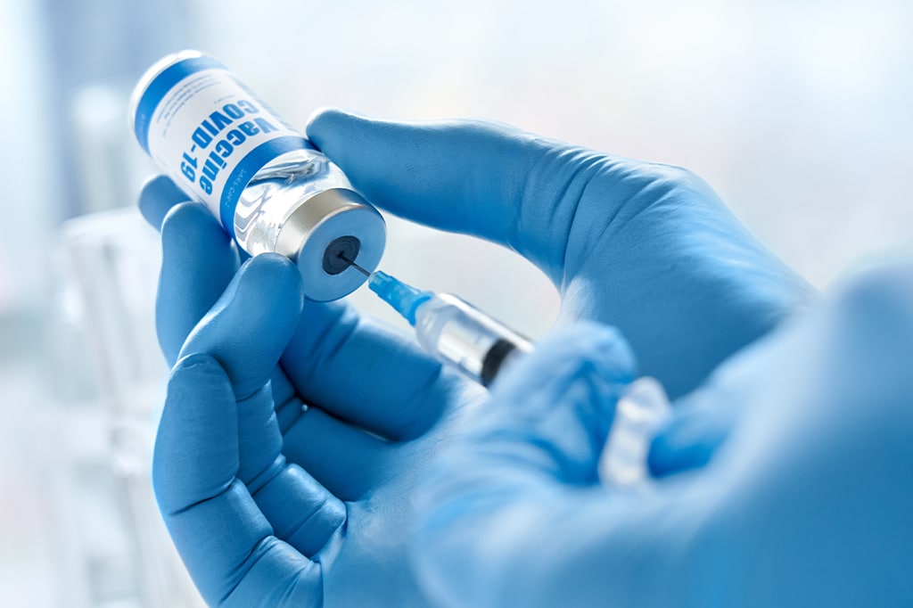 COVIDワクチンを注射器に注入する医師のクローズアップ