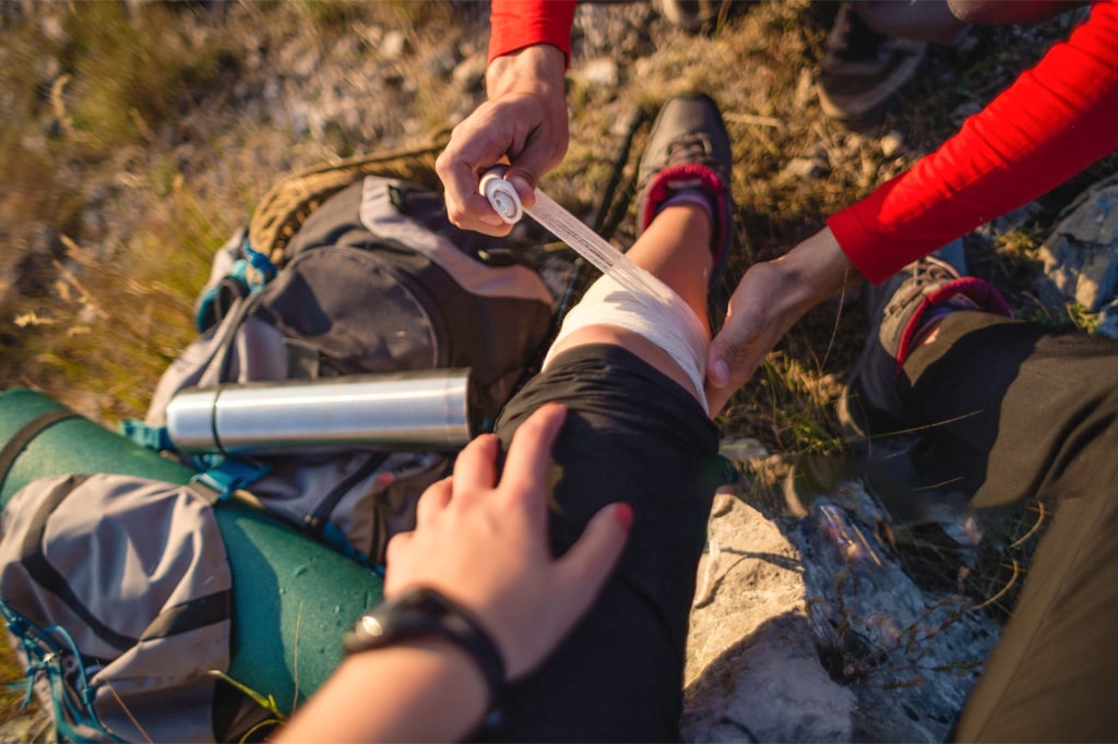 Guide bandaging up hikers leg after an mountain climbing injury 1