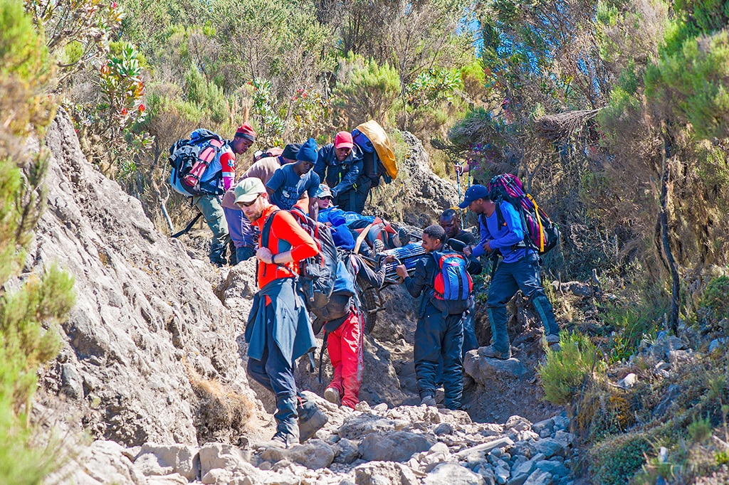 Kilimanjaro mountain crew evacuating an injured female hiker in a stroller type stretcher