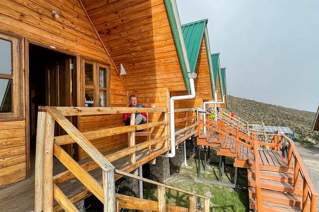 Mannelijke wandelaar ontspant op de galerij na een wandeling bergopwaarts bij een nieuwe Horombo-hut.jpg