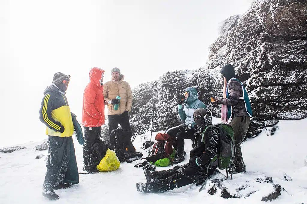 Toeristische wandelaars en de Easy Travel-gids op Uhuru Peak van de Kilimanjaro.jpg