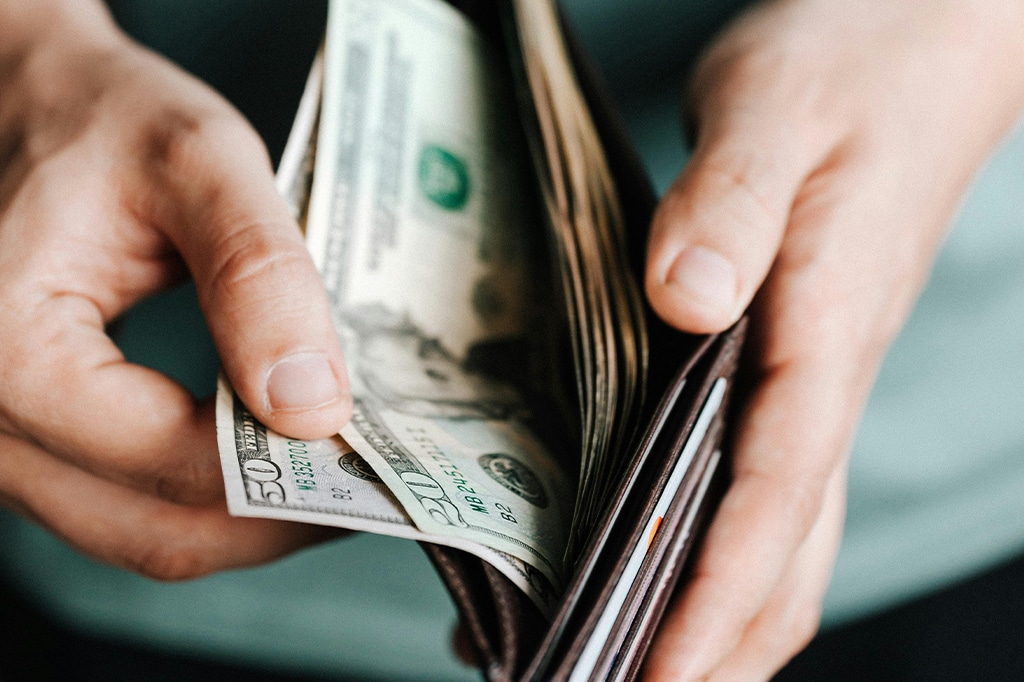 Close-up of a man putting us dollars into his wallet