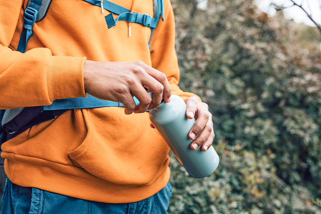 Close up of a young hiker opening his water bottle Close up of a young hiker opening his water bottle