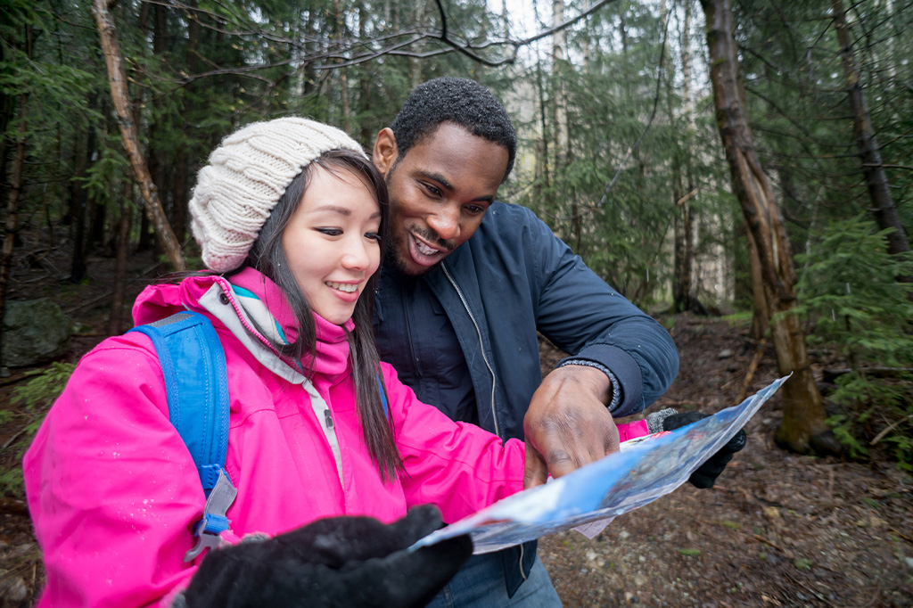 Easy Travel mountain guide showing the route plan to the young woman hiker Easy travel mountain guide showing the route plan to the young woman hiker