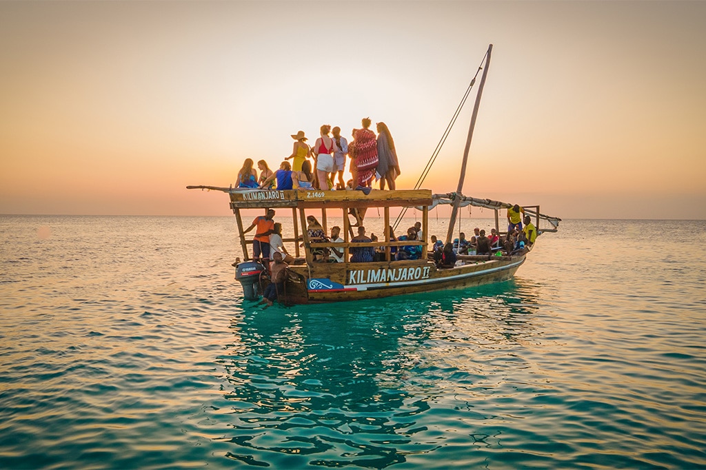 A group of tourists enjoying a sunset dhow cruise in Zanzibar, Tanzania
