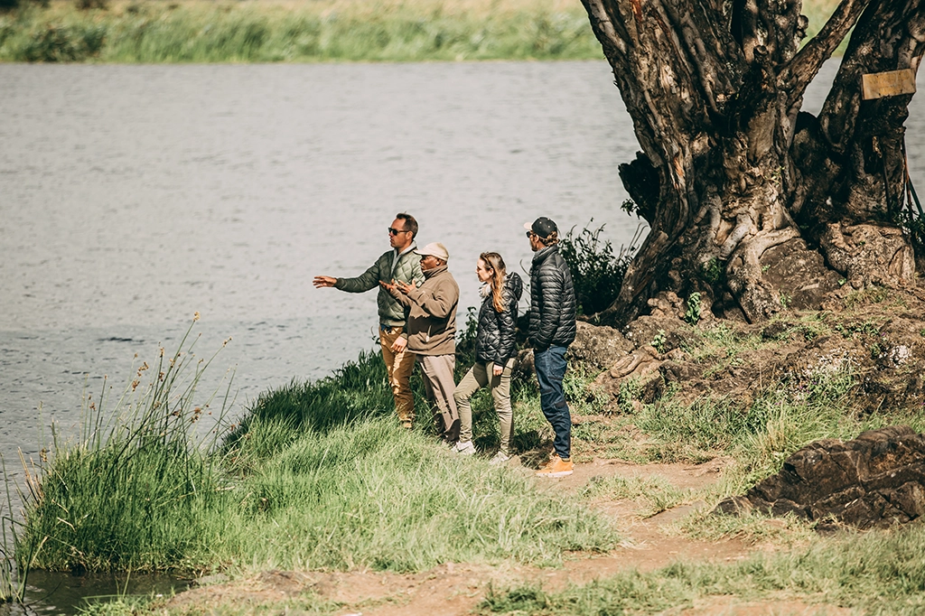 Easy Travel safarigids die toeristen iets uitlegt aan de rand van een waterlichaam Easy Travel safarigids die toeristen iets uitlegt aan de rand van een waterlichaam