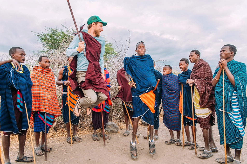 Toeristen en Maasai-krijgers voeren de traditionele springdans Adumu uit Toeristen en Maasai-krijgers voeren de traditionele springdans (Adumu) uit
